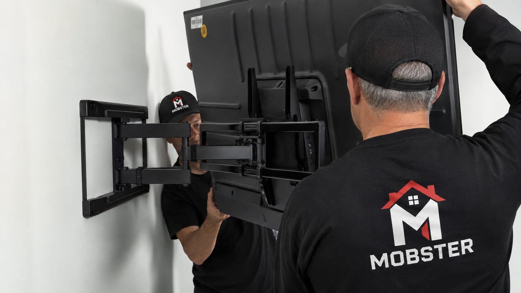 Two Mobsters fitting a television onto a full-motion wall arm
