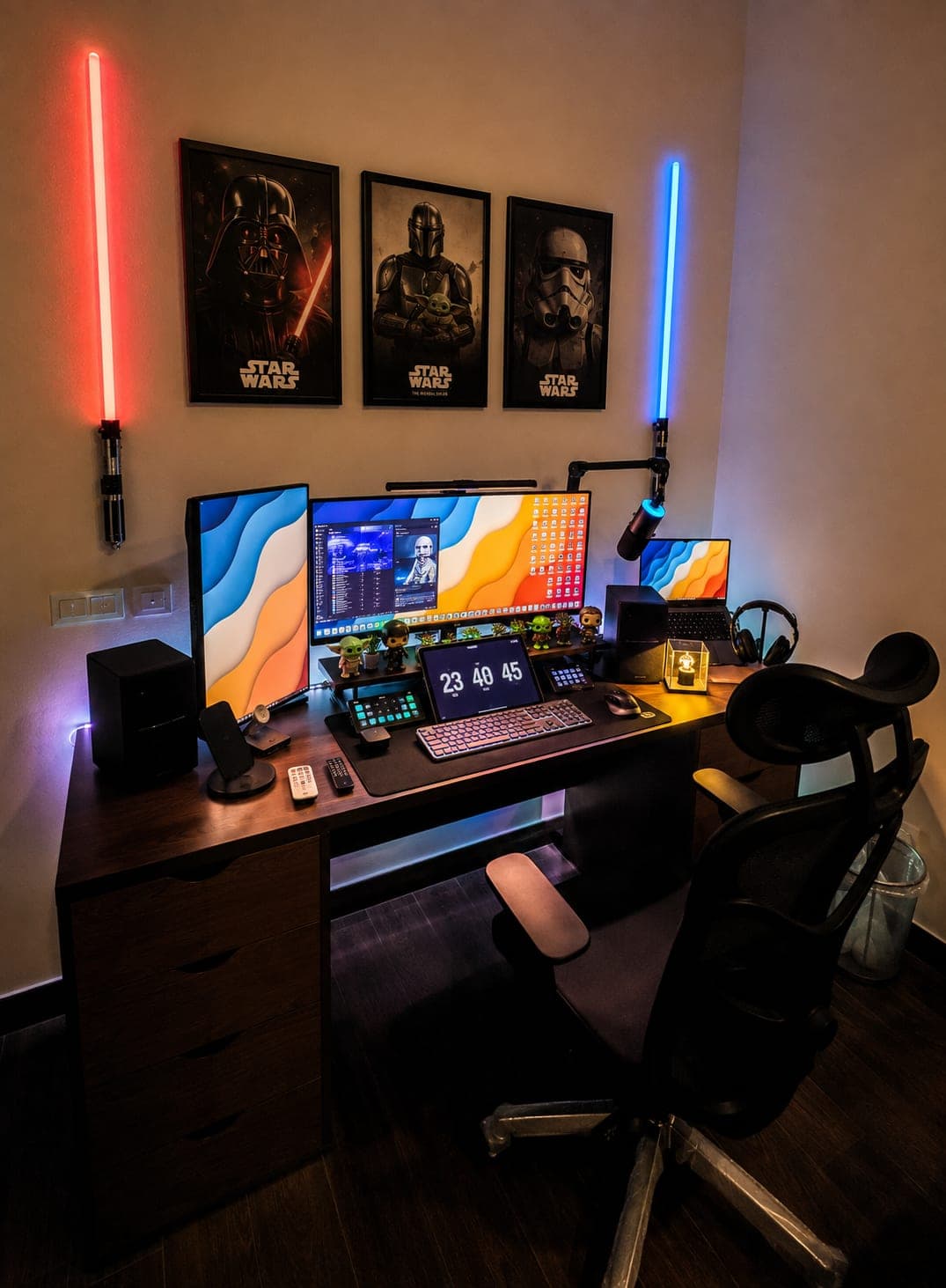 A finished home office with three mounted monitors, framed posters and backlit wall fixtures